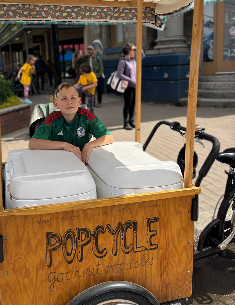 a kid sitting behind a icebox bicycle setup